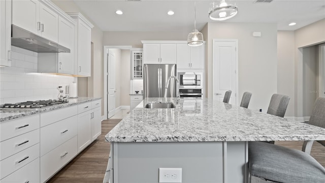 kitchen with a kitchen bar, a large island with sink, white cabinetry, and appliances with stainless steel finishes