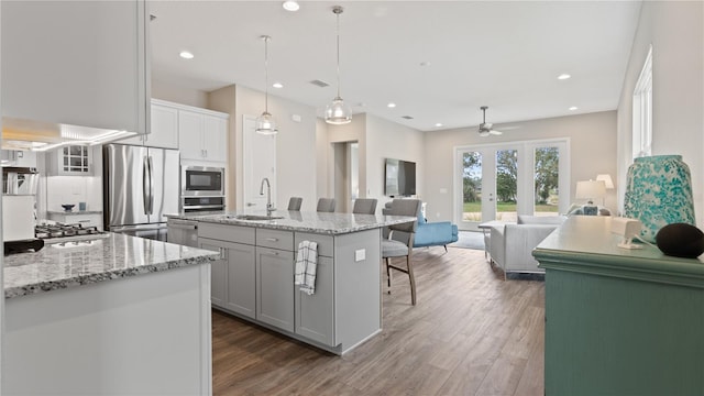 kitchen featuring appliances with stainless steel finishes, dark hardwood / wood-style flooring, a breakfast bar, a kitchen island with sink, and sink