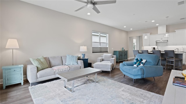 living room with ceiling fan and dark wood-type flooring