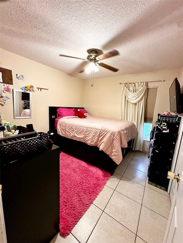 bedroom with a textured ceiling, light tile patterned floors, and ceiling fan