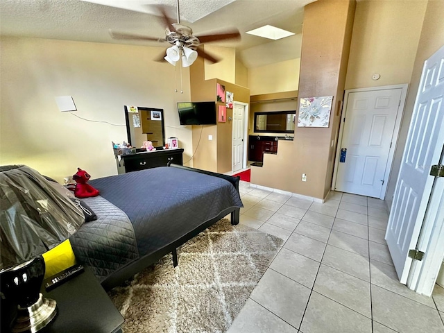 tiled bedroom with ceiling fan, high vaulted ceiling, a textured ceiling, and a skylight