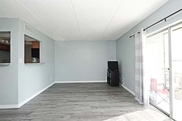 unfurnished room featuring a textured ceiling and light hardwood / wood-style flooring