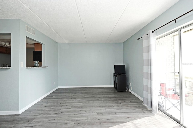 unfurnished room featuring visible vents, baseboards, wood finished floors, and a wealth of natural light