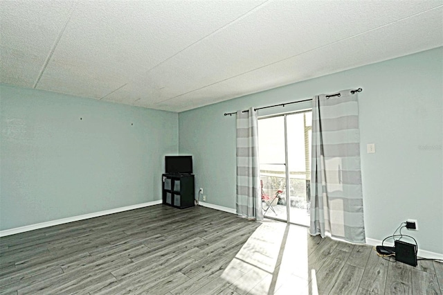 empty room featuring baseboards, a textured ceiling, and wood finished floors