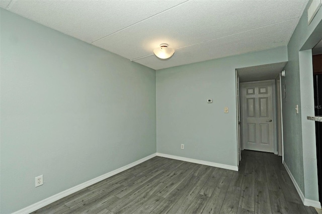 spare room featuring baseboards and dark wood-type flooring