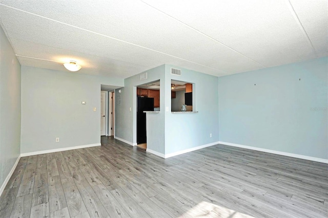 unfurnished living room featuring baseboards, visible vents, and wood finished floors