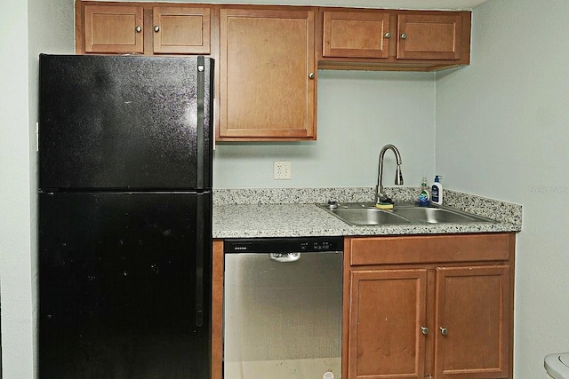 kitchen with stainless steel dishwasher, brown cabinets, a sink, light countertops, and freestanding refrigerator