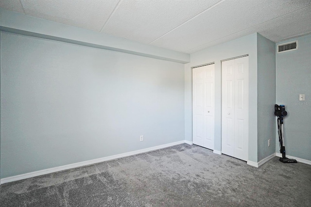 unfurnished bedroom featuring carpet floors, baseboards, multiple closets, and visible vents