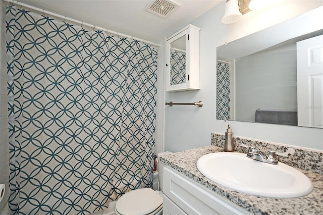 bathroom with a textured ceiling, curtained shower, vanity, and toilet