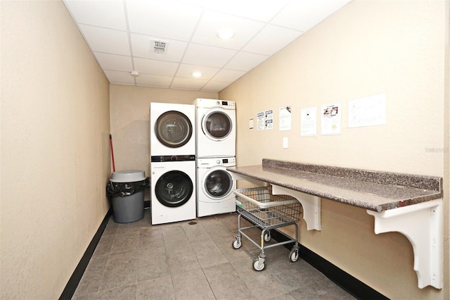 clothes washing area with stacked washer and clothes dryer and light tile patterned floors