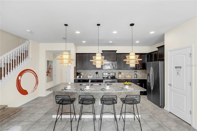 kitchen with dark brown cabinetry, a kitchen bar, a kitchen island with sink, and stainless steel appliances