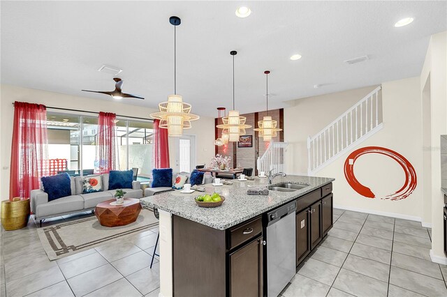 kitchen featuring dark brown cabinetry, an island with sink, stainless steel dishwasher, decorative light fixtures, and ceiling fan with notable chandelier