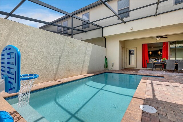 view of pool with glass enclosure, ceiling fan, and a patio