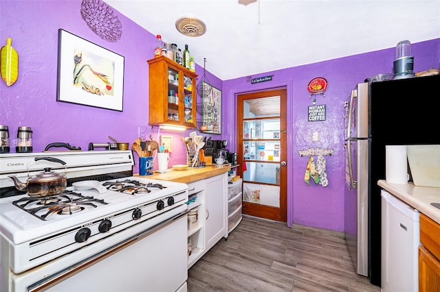 kitchen with light wood-type flooring, white appliances, and white cabinets