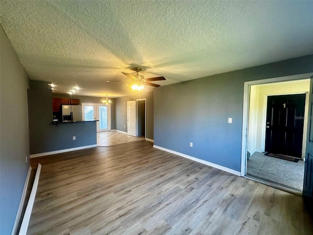 unfurnished living room featuring light hardwood / wood-style floors, ceiling fan, and a textured ceiling