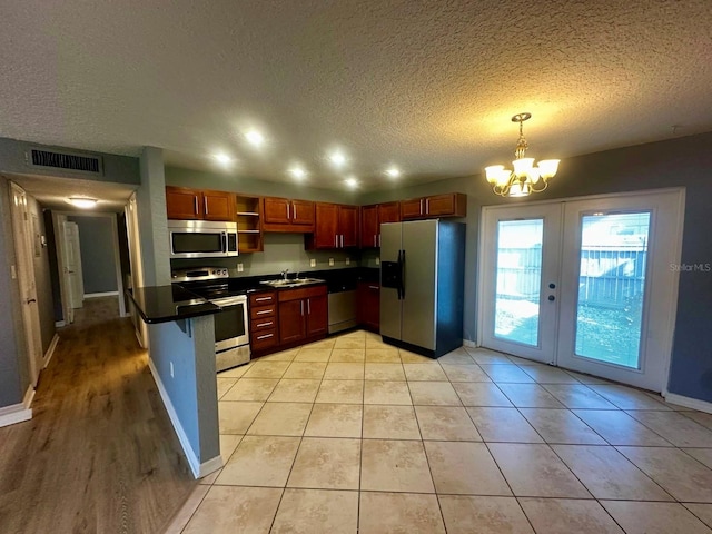 kitchen featuring a textured ceiling, sink, hanging light fixtures, an inviting chandelier, and appliances with stainless steel finishes