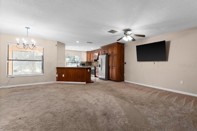 interior space with light colored carpet, a textured ceiling, and ceiling fan with notable chandelier