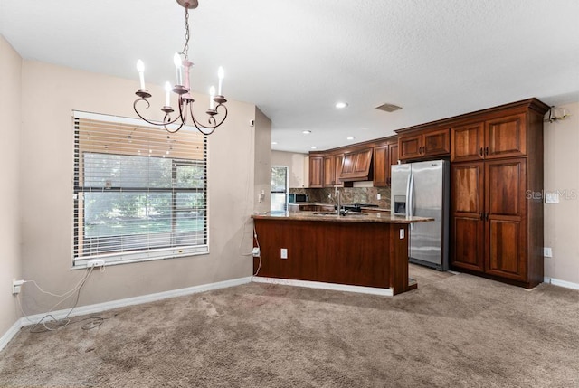 kitchen featuring pendant lighting, kitchen peninsula, stainless steel fridge with ice dispenser, light colored carpet, and an inviting chandelier