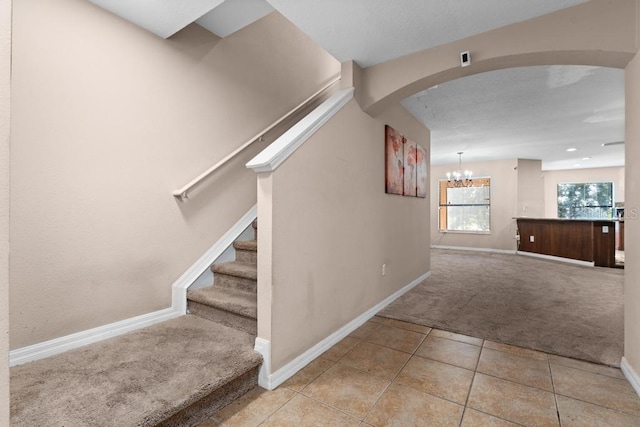 stairs with carpet and a chandelier