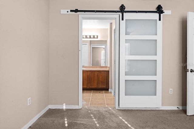 interior space featuring light colored carpet, a barn door, and ensuite bathroom