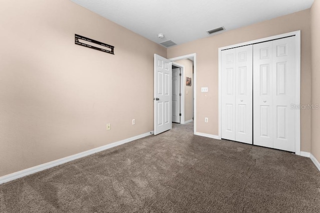 unfurnished bedroom with a closet and dark colored carpet