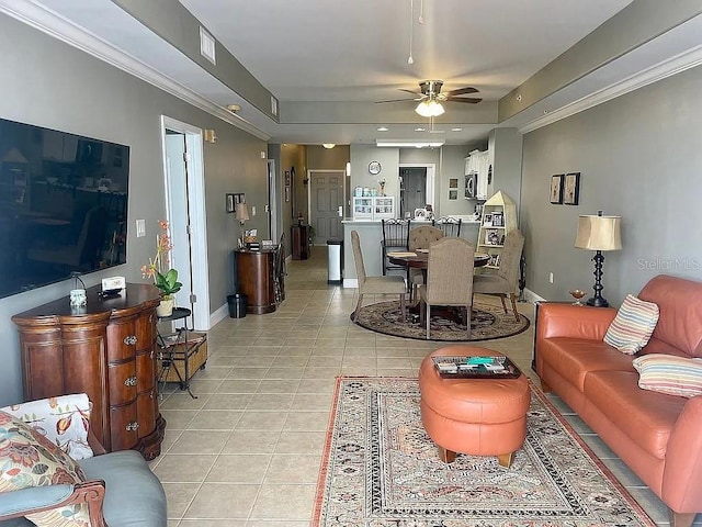 tiled living room featuring crown molding, a tray ceiling, and ceiling fan