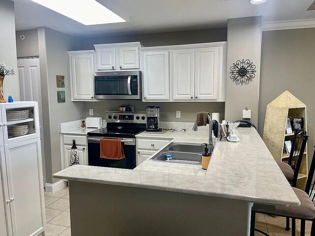 kitchen featuring stainless steel appliances, white cabinetry, a kitchen bar, and sink