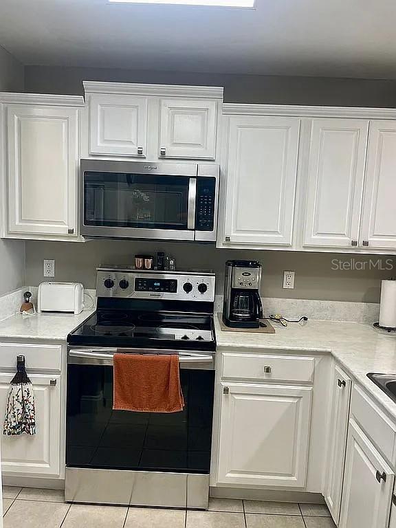 kitchen with white cabinets, appliances with stainless steel finishes, and light tile patterned floors