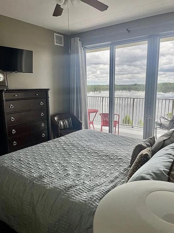 bedroom featuring multiple windows, a water view, ceiling fan, and access to exterior