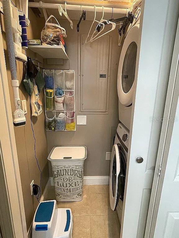 laundry area with stacked washer / dryer and light tile patterned floors