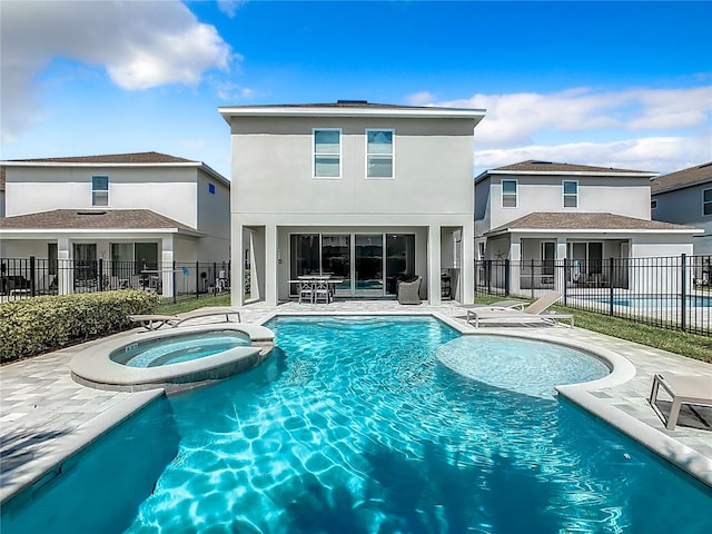 back of property featuring a patio area and a pool with hot tub