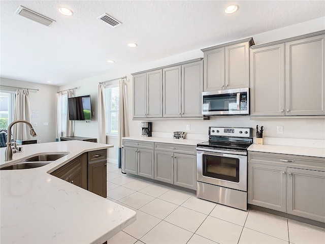 kitchen featuring gray cabinetry, stainless steel appliances, light tile patterned flooring, and sink