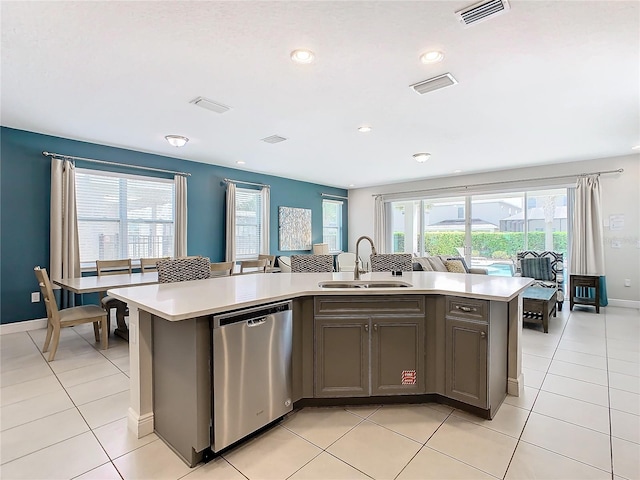 kitchen featuring a kitchen island with sink, dishwasher, light tile patterned floors, and sink