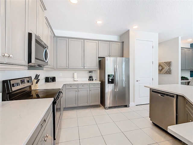 kitchen with light tile patterned flooring, appliances with stainless steel finishes, and gray cabinetry