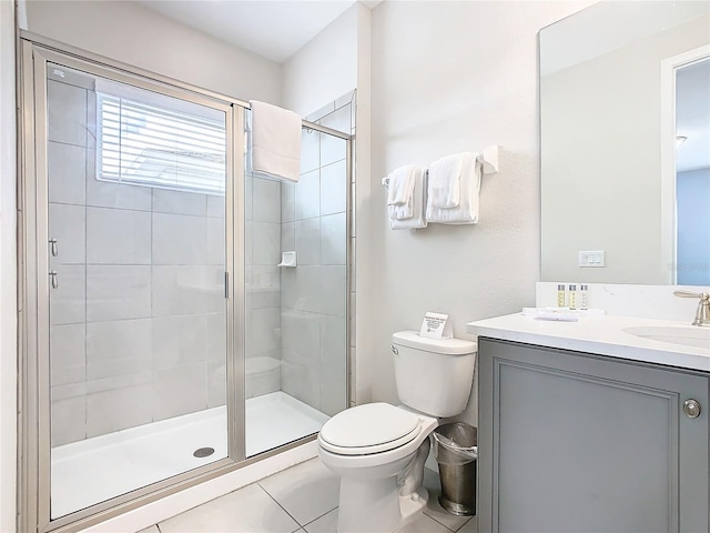 bathroom featuring tile patterned flooring, vanity, toilet, and a shower with shower door