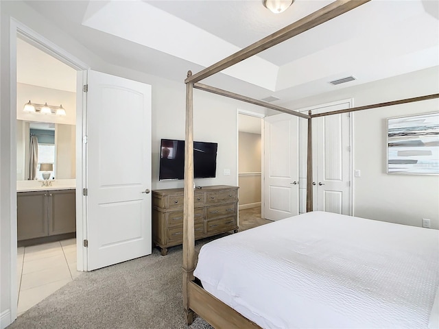 bedroom featuring light carpet and ensuite bathroom