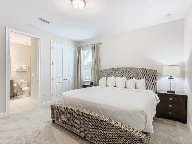 carpeted bedroom with connected bathroom and a textured ceiling