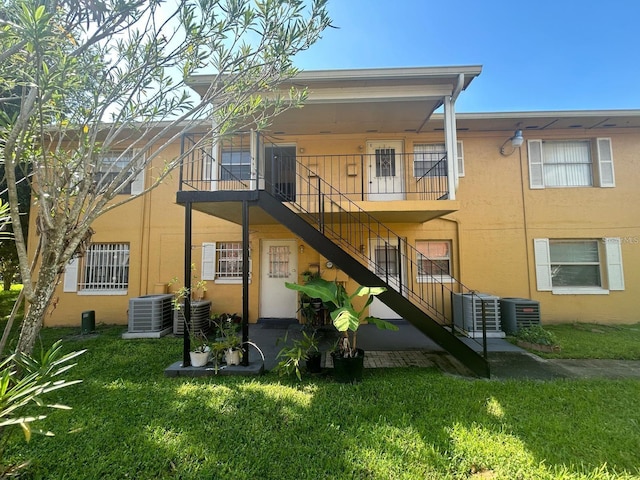 rear view of house featuring a balcony, central AC, and a yard