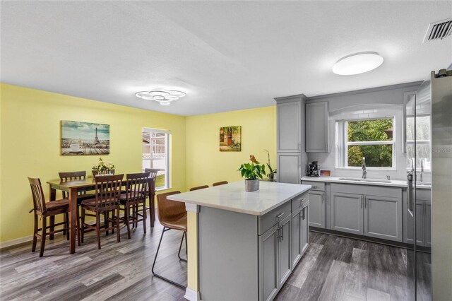 kitchen featuring sink, gray cabinetry, a kitchen breakfast bar, and dark hardwood / wood-style flooring