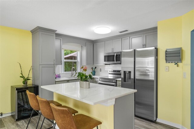 kitchen with light hardwood / wood-style floors, sink, appliances with stainless steel finishes, and tasteful backsplash