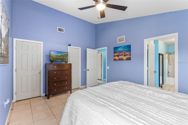 bedroom featuring ceiling fan, light tile patterned flooring, lofted ceiling, and ensuite bathroom