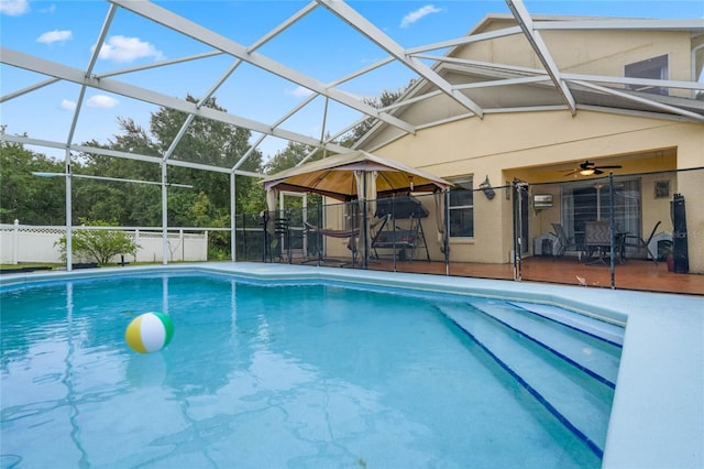 view of pool with glass enclosure, ceiling fan, and a patio