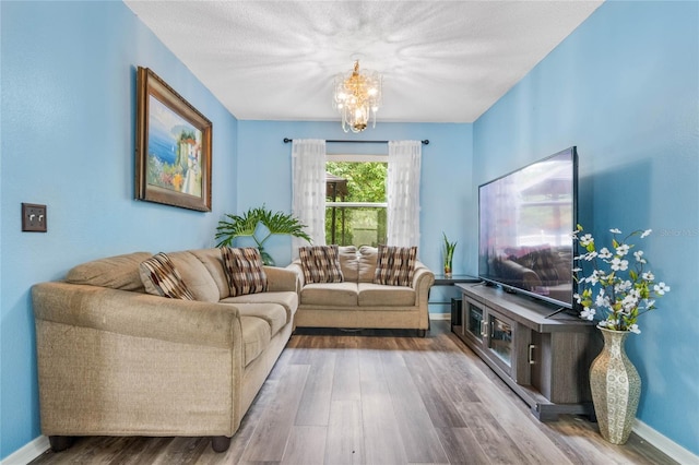 living room featuring hardwood / wood-style flooring, a textured ceiling, and a notable chandelier