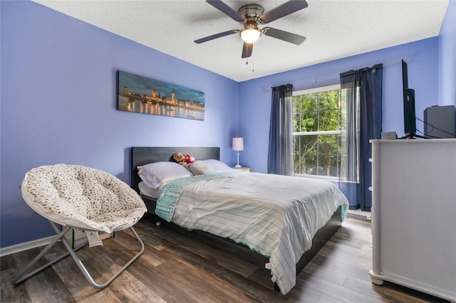 bedroom with ceiling fan, a textured ceiling, and dark hardwood / wood-style flooring