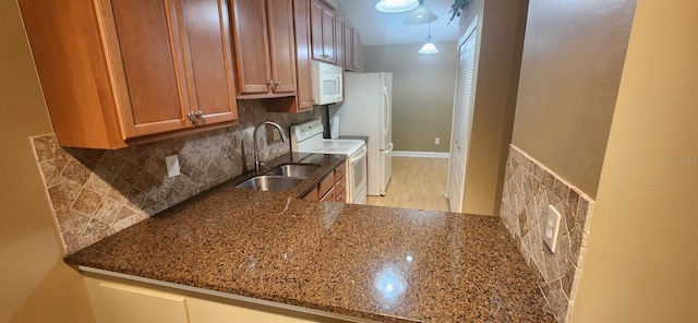 kitchen featuring white appliances, tasteful backsplash, sink, dark stone counters, and light hardwood / wood-style flooring