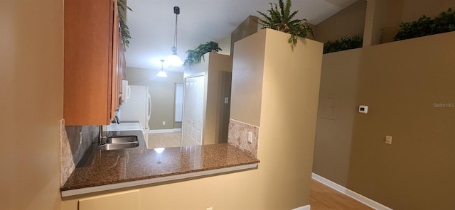 kitchen with tasteful backsplash, sink, kitchen peninsula, light hardwood / wood-style floors, and decorative light fixtures