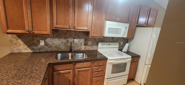 kitchen with decorative backsplash, dark stone countertops, sink, and white appliances