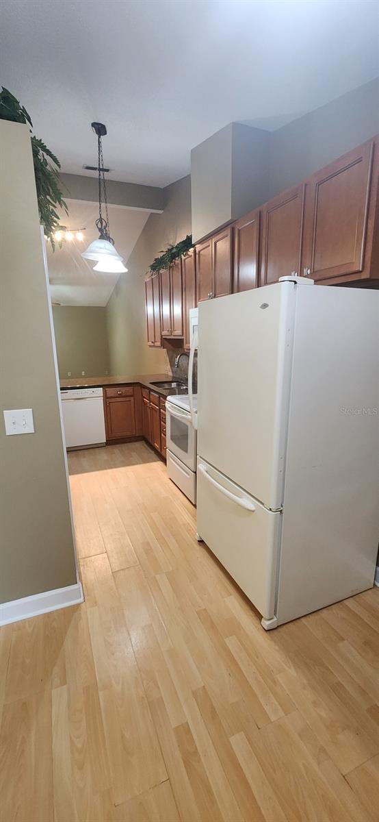 kitchen featuring hanging light fixtures, vaulted ceiling, light hardwood / wood-style flooring, sink, and white appliances