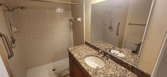 bathroom featuring vanity, toilet, and tiled shower