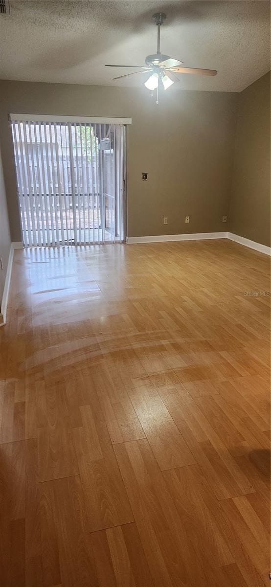 spare room featuring a textured ceiling, light wood-type flooring, and ceiling fan